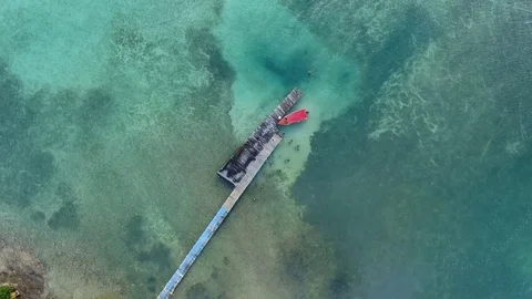 Aerial top of view of a small red boat reaching the wooden pier, Martinique Stock Footage 82658723