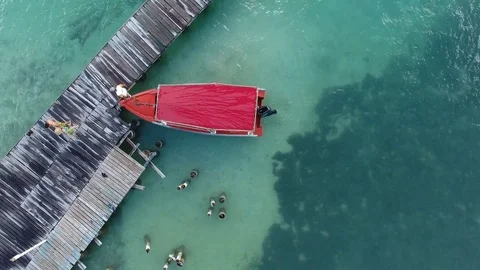 Aerial top of view of a small red boat reaching the wooden pier, Martinique Stock Footage 82658744