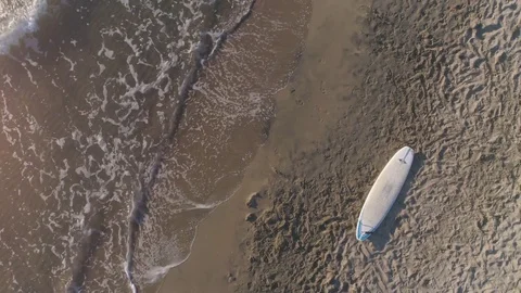 Aerial top view of surf board lying down on the sand at the beach at sunset Vídeos de archivo 85117024