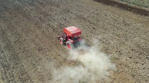 Aerial top view of tractor cutting furrows in farm field for sowing farm Stock Footage 133845652