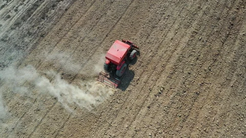 Aerial top view of tractor cutting furrows in farm field for sowing farm Stock Footage 133845744
