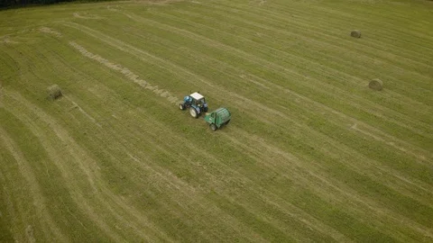 Aerial top view of tractor rides on field after harvesting and makes haystacks. Stockbeeldmateriaal 124663192