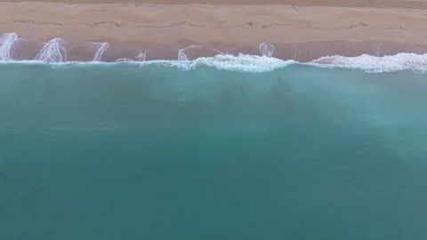 Aerial Top View of Turquoise Waves Meeting Sandy Shore Stock Footage 329285867