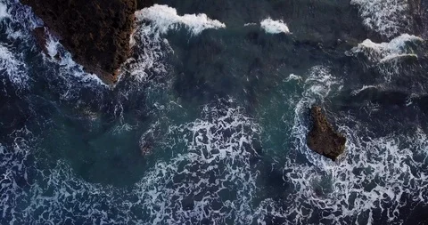 Aerial top view waves break on dark rocks near beach. Sea waves on the danger Vídeo Stock 93286396
