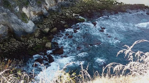 Aerial top view waves break on dark rocks near beach. Sea waves on the dangerous Stock Footage 118399198