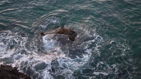 Aerial top view waves break on dark rocks near beach Stock Footage 124550123