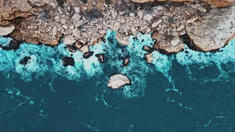 Aerial top view of waves break on rocks in a blue ocean. Stock Footage 147934710