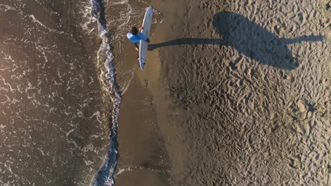 Aerial top view of Young man surfer wearing wetsuit carrying surf board at the Stock Footage 90219853