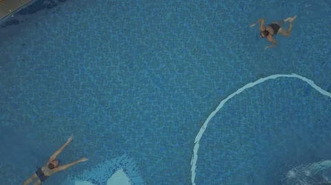 Aerial top view of young man and young brunette girl swimming in the pool Stock Footage 97907616