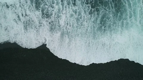 Aerial topdown epic waves oceanic foam hit dark pebble beach sea storm seascape Video stock 145767946