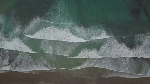 Aerial topdown footage camera move left along the coast line with upcoming waves Stock Footage 85304093