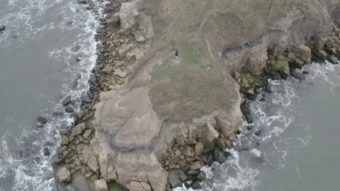 Aerial topdown spin tracking person on coastal cliff sea drone UK NCL DJI 0217 B Video stock 140287517