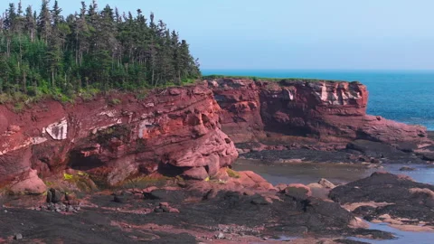 Aerial touring around the red cliffs of Duckpond Beach in the Maritimes of Stock Footage 289081312