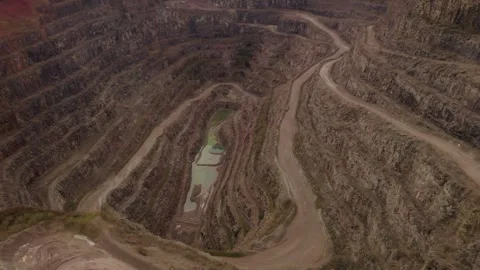 Aerial tow down view fly over deep quarry site with no machinery and gravel road Stock-Footage 251042016