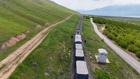 Aerial Tracking Above Freight Train Through Apricot Orchards and Snowy Mountains Stock Footage 340525506
