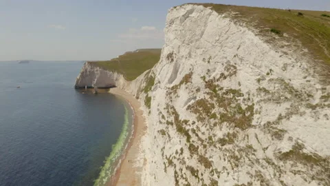 Aerial tracking close to a dramatic white chalk cliff face by the sea on the Vídeos de archivo 144769848