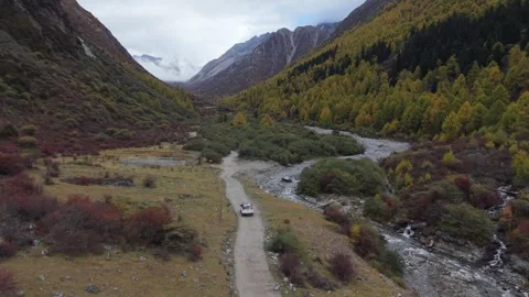 Aerial Tracking Drone Shot of Off-Road Vehicle Driving Through Autumn Mountain Stock Footage 320352276