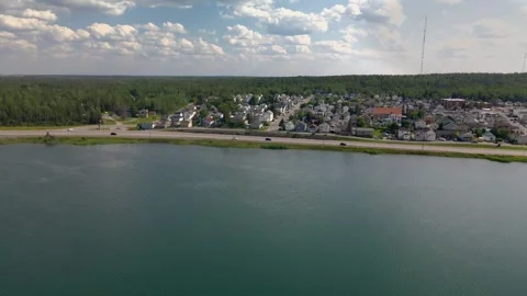 Aerial: tracking left to right over pond with small town in foreground. Stock Footage 254908812