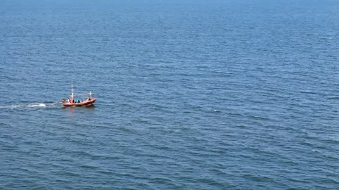 Aerial tracking motion around of a small fishing boat floating by blue sea water Stock Footage 311039757