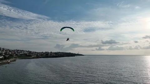 Aerial tracking of a paramotor flying over the sea with a drone Vídeo Stock 266389498