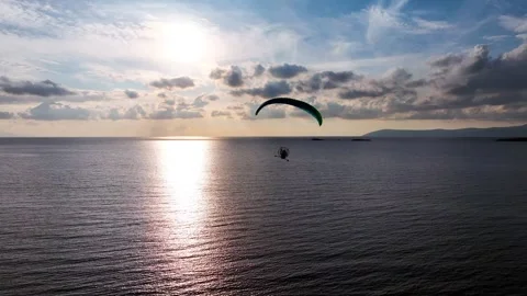 Aerial tracking of a paramotor flying over the sea with a drone Stock Footage 266389802