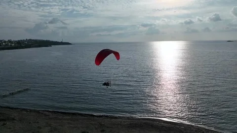 Aerial tracking of a paramotor flying over the sea with a drone Stock Footage 266389839