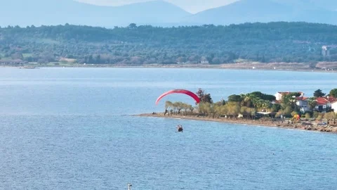 Aerial tracking of a paramotor flying over the sea with a drone Stock Footage 266390018