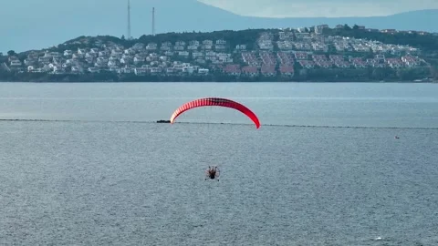 Aerial tracking of a paramotor flying over the sea with a drone Stock Footage 266390159