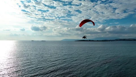 Aerial tracking of a paramotor flying over the sea with a drone Stockbeeldmateriaal 266390442