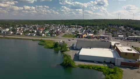 Aerial: tracking right to left over pond with small town in foreground. Stock Footage 254908817