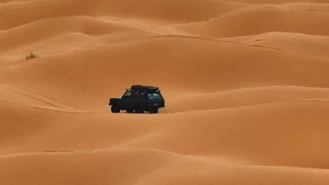 Aerial tracking shot of a black Range Rover Classic crossing the vast Sahara 動画素材 335444869