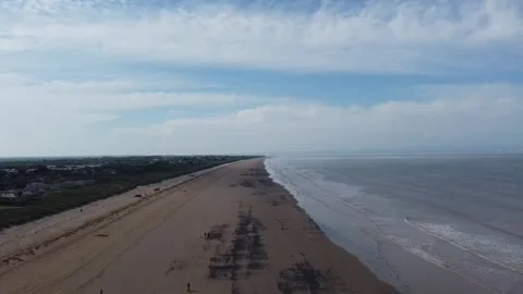 Aerial tracking shot flying over the vast dark sand shoreline and gentle waves Stock Footage 329983813
