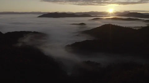 Aerial tracking shot of low clouds and fog in mountains at sunrise Video stock 118861396