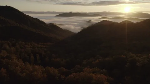 Aerial tracking shot of low clouds and fog in mountains at sunrise Video stock 118861573