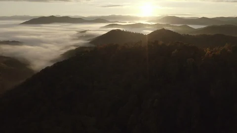 Aerial tracking shot of low clouds and fog in mountains at sunrise Video stock 118861636