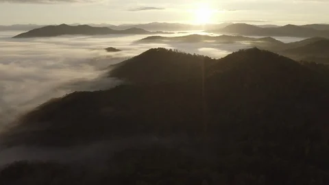 Aerial tracking shot of low clouds and fog in mountains at sunrise Video stock 118866567