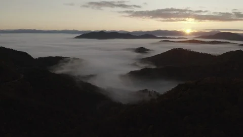 Aerial tracking shot of low clouds and fog in mountains at sunrise Video stock 118871631
