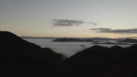 Aerial tracking shot of low clouds and fog in mountains at sunrise 스톡 동영상 118871642