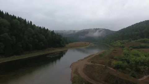Aerial tracking shot of mountain river flowing between the mountains covered Video stock 75477573