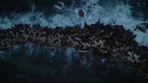 Aerial Tracking Shot of Rough Waves Breaking Over Tetrapod Breakwater Stock Footage 340263888