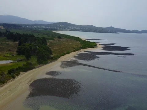 Aerial Tracking Shot of Sandy Beach with rocks and still water Stock Footage 76011599