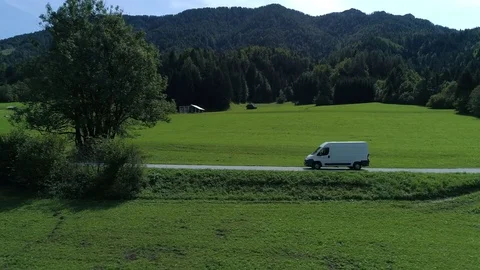 Aerial - Tracking shot from the side of delivery van driving on a beautiful road Stock Footage 80402903
