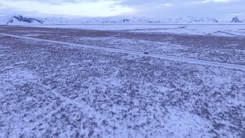 Aerial tracking shot of single car on ice road in deserted landscape Stock Footage 82903729