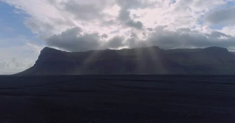 Aerial tracking shot of sun rays shining through clouds over mountains Video stock 79835106