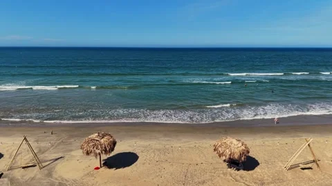 Aerial tracking shot of thatched beach umbrellas on empty white sand 4K Stock Footage 336598630