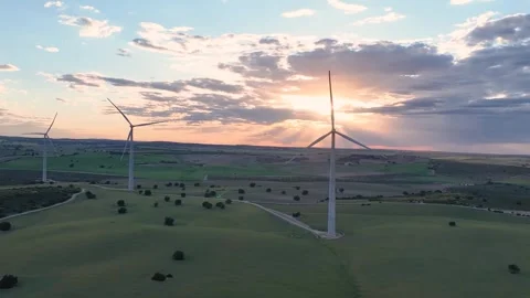 Aerial tracking shot of three wind turbines with the setting through clouds Video stock 274193952