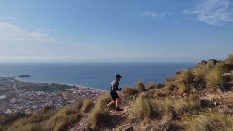 Aerial Tracking Shot of Trail Runner on Mountain Ridge with Coastal Sea View Stock Footage 345026426