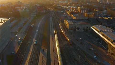 Aerial tracking shot of train leaving a railway station into the setting sun Stock Footage 98905736