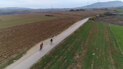 Aerial tracking shot of two cyclists riding down a rural road Stock Footage 113045258
