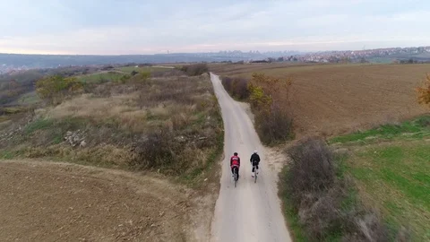 Aerial tracking shot of two cyclists riding down a rural road Stock Footage 113045327